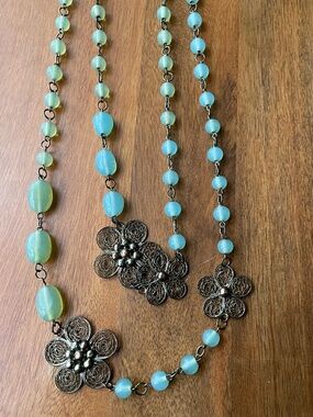 beaded necklace with light blue glass beads and detailed metal filigree flowers